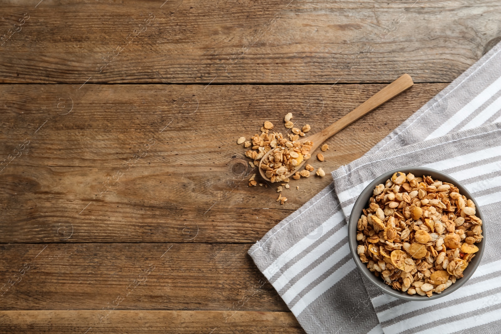 Photo of Ceramic bowl with granola on wooden table, flat lay and space for text. Cooking utensils