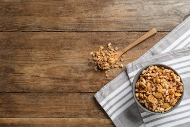 Ceramic bowl with granola on wooden table, flat lay and space for text. Cooking utensils