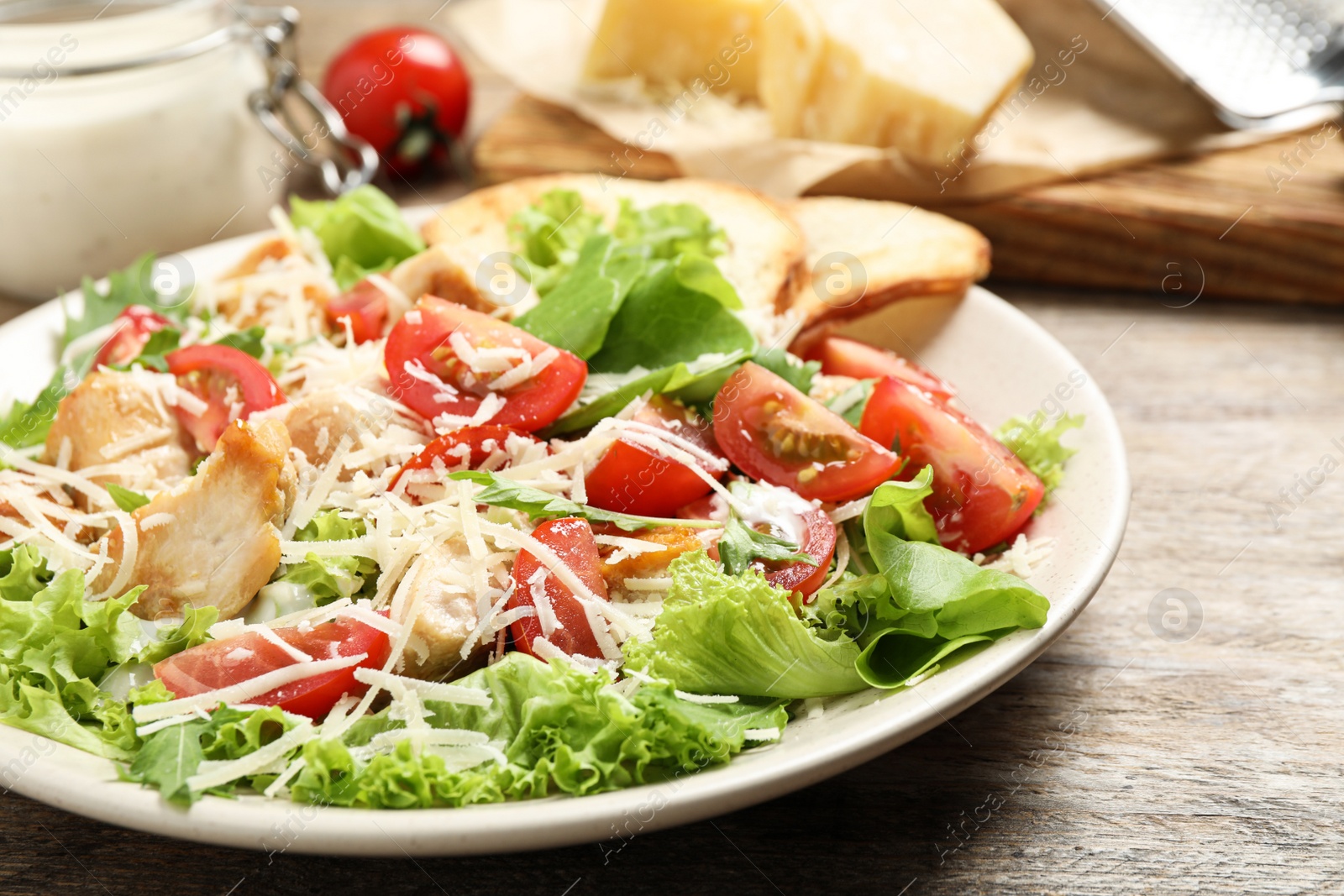 Photo of Delicious fresh Caesar salad on wooden table, closeup