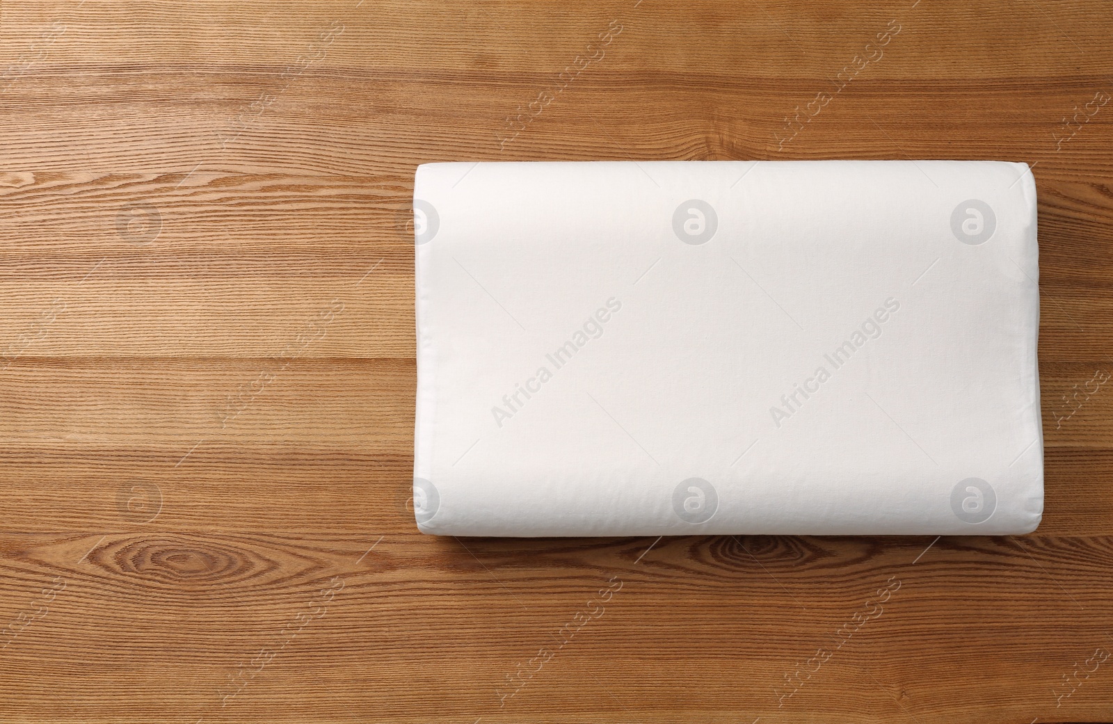 Photo of Soft bed pillow on wooden background with space for text