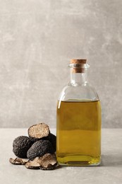 Photo of Fresh truffles and oil on light grey table