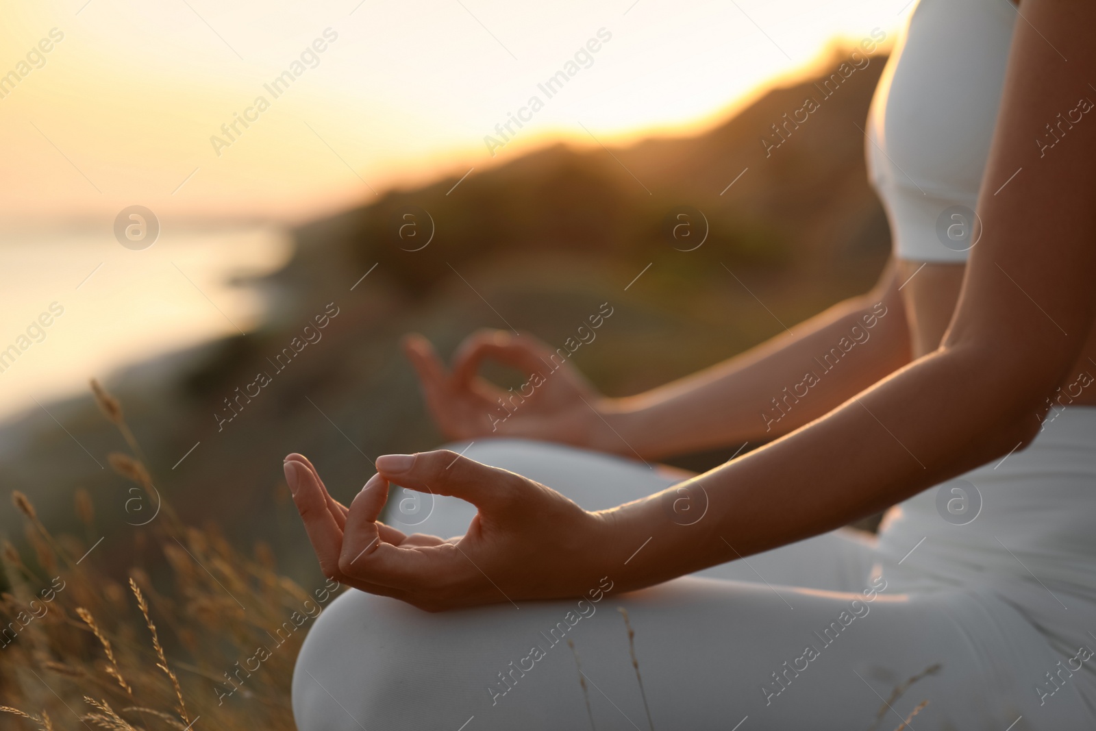 Photo of Woman meditating outdoors at sunset, closeup view