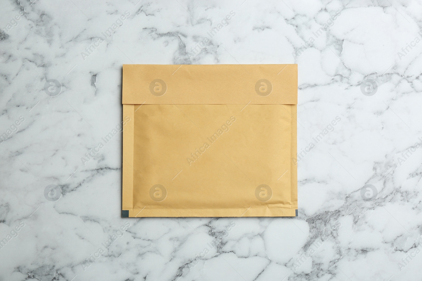 Photo of Kraft paper envelope on white marble background, top view