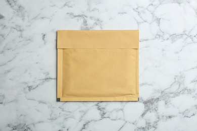 Kraft paper envelope on white marble background, top view
