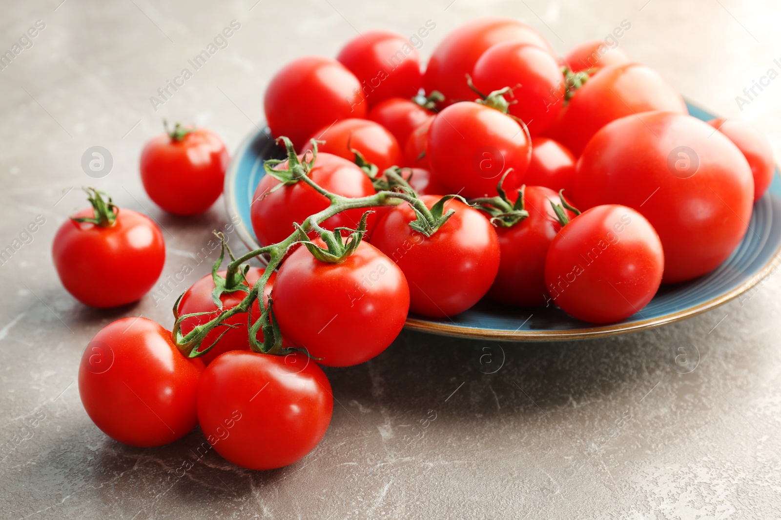 Photo of Plate with fresh ripe tomatoes on grey background