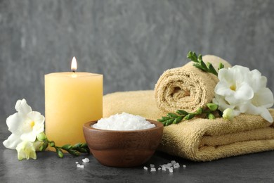 Composition with different spa products and burning candle on grey table