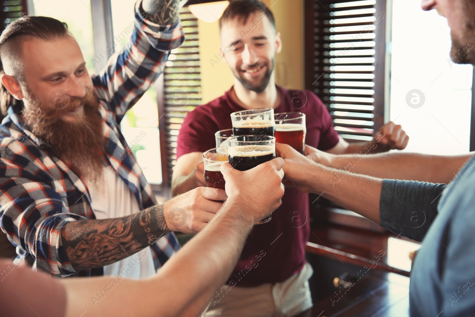 Photo of Friends clinking glasses with beer in pub