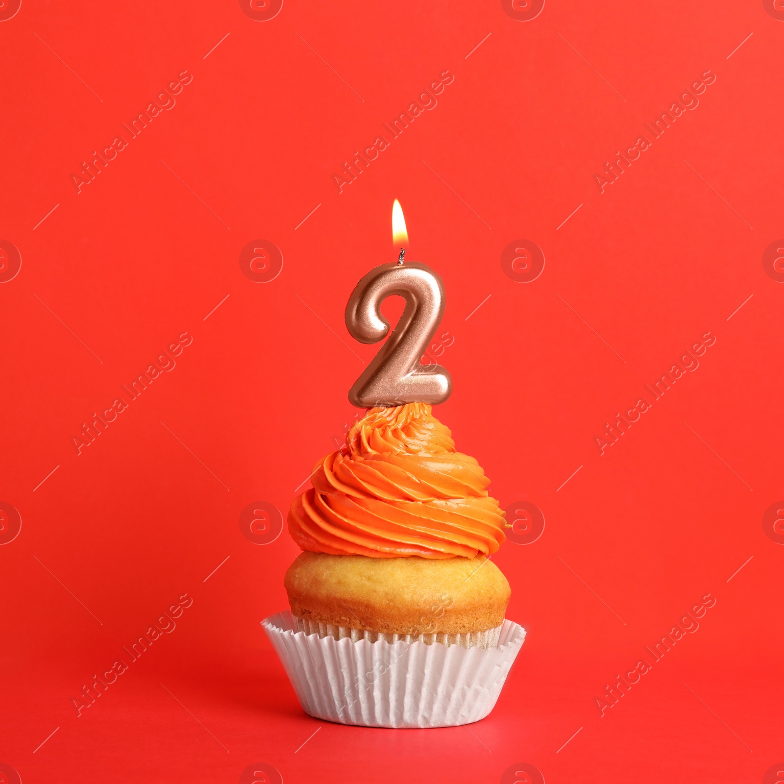 Photo of Birthday cupcake with number two candle on red background