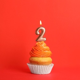 Photo of Birthday cupcake with number two candle on red background