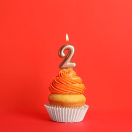 Birthday cupcake with number two candle on red background