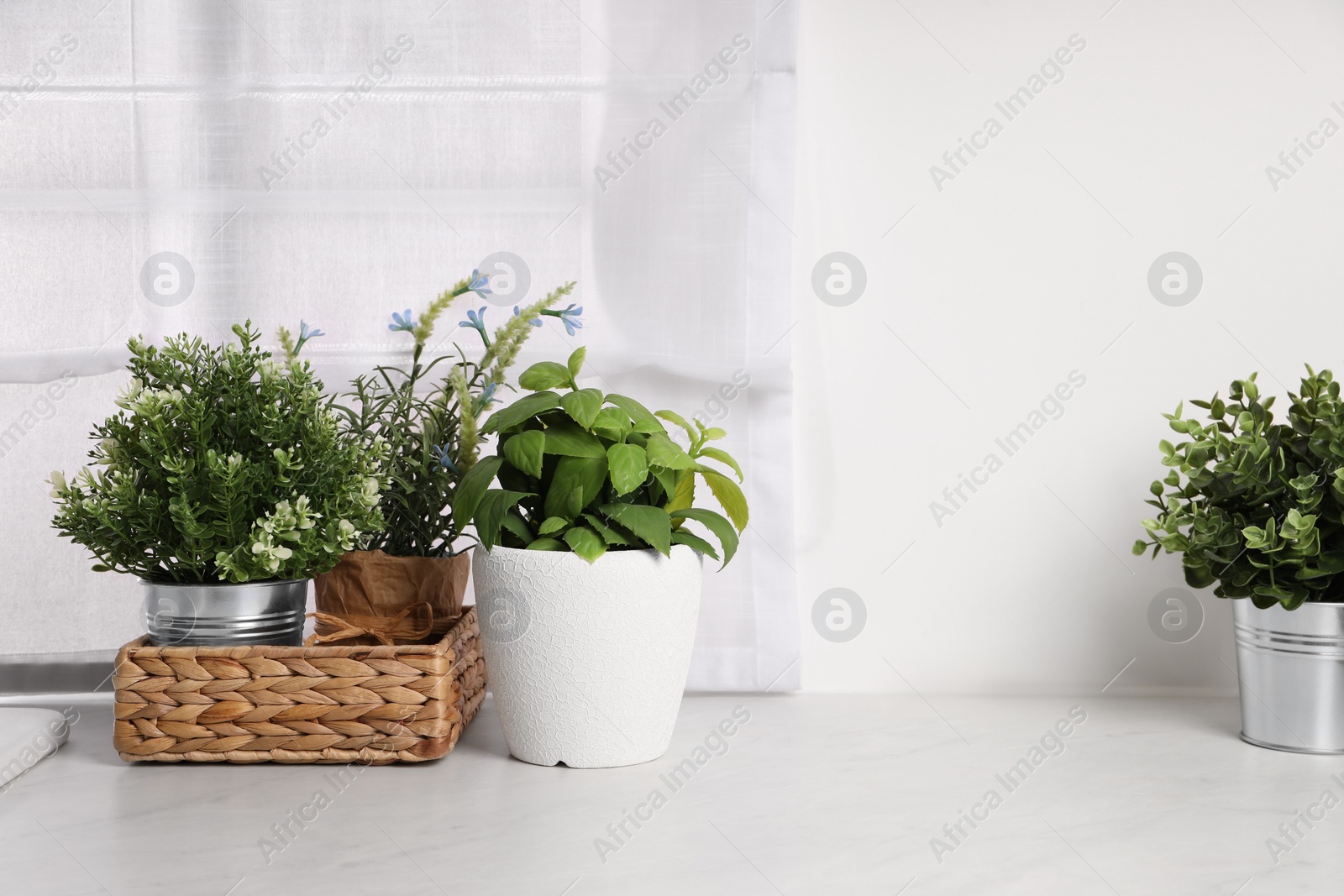 Photo of Artificial potted herbs on white marble countertop in kitchen. Home decor