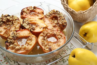 Photo of Delicious baked quinces with nuts in bowl and fresh fruits on table, closeup