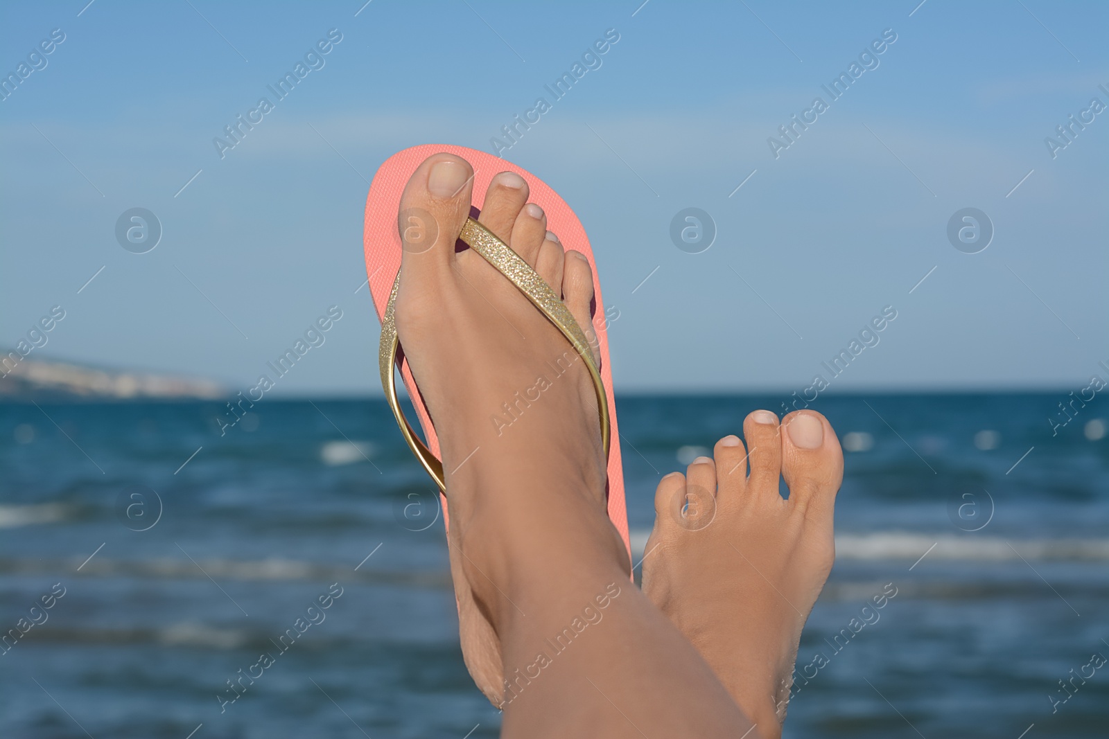 Photo of Woman wearing stylish flip flop near sea, closeup