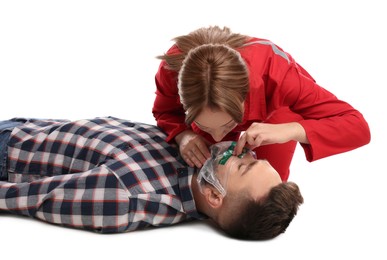 Photo of Paramedic in uniform performing first aid on unconscious man against white background