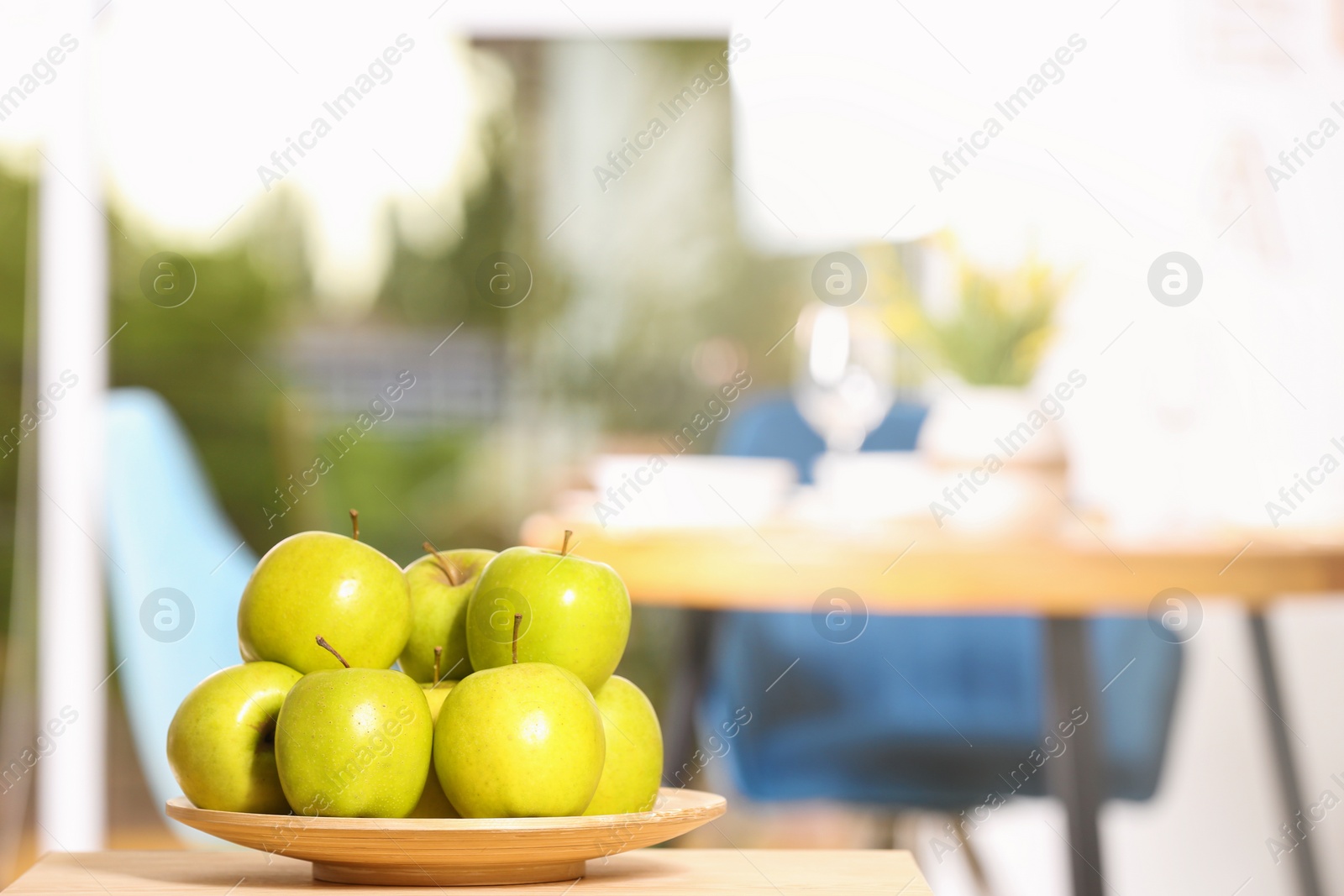 Photo of Plate with sweet green apples on table in room, space for text