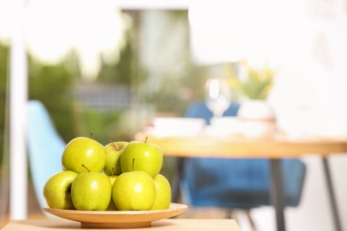 Photo of Plate with sweet green apples on table in room, space for text