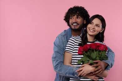 Photo of International dating. Happy couple with bouquet of roses on pink background, space for text