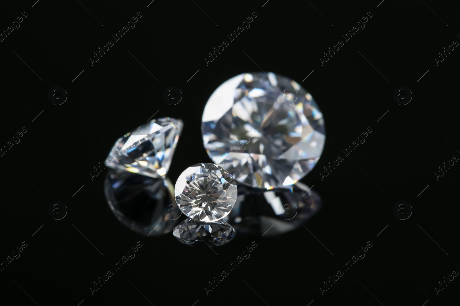 Photo of Beautiful shiny diamonds on black mirror surface