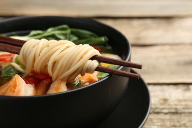 Bowl of delicious ramen with chopsticks on table, closeup and space for text. Noodle soup