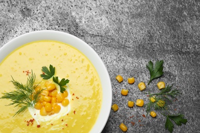 Photo of Delicious creamy corn soup served on grey table, flat lay