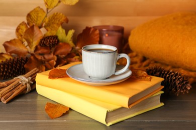 Composition with cup of hot coffee, books and autumn leaves on wooden table