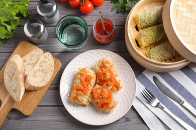 Photo of Delicious cabbage rolls served on wooden table, flat lay