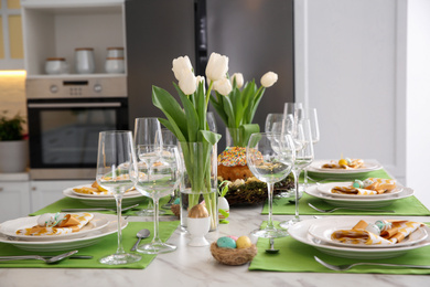 Photo of Festive Easter table setting with floral decor in kitchen