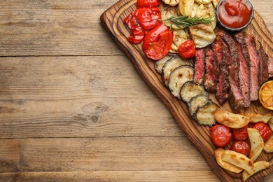 Photo of Delicious grilled beef with vegetables, spices and tomato sauce on wooden table, top view. Space for text