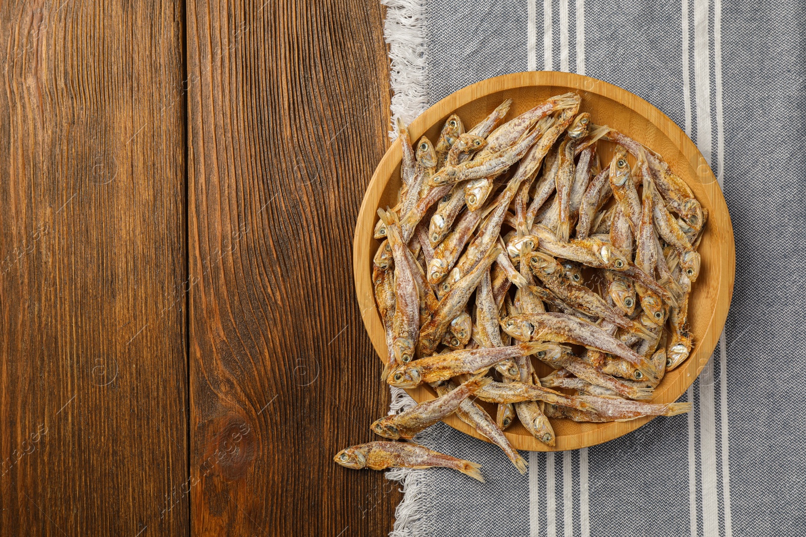 Photo of Tasty dried anchovies on wooden table, top view. Space for text