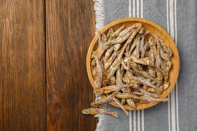 Tasty dried anchovies on wooden table, top view. Space for text