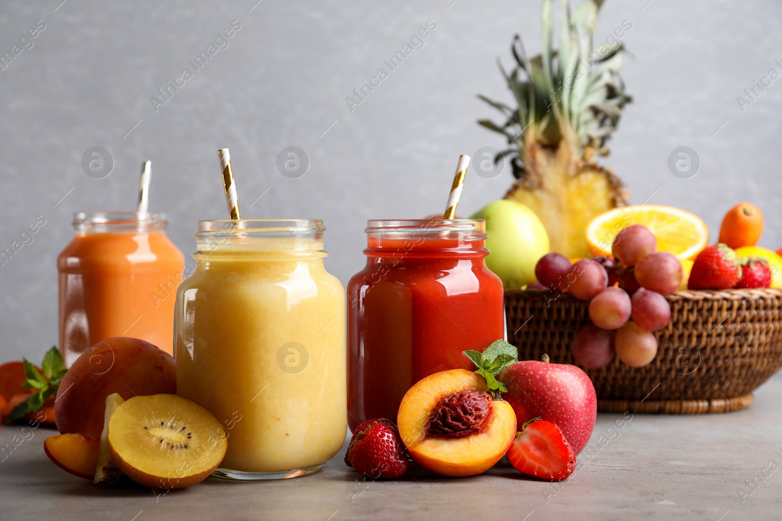 Photo of Delicious juices and fresh ingredients on grey table