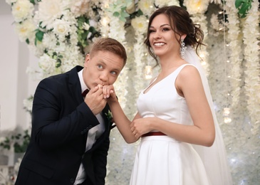 Man kissing his bride's hand at altar on wedding ceremony