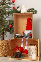 Photo of Christmas gnome and festive decoration in wooden boxes indoors