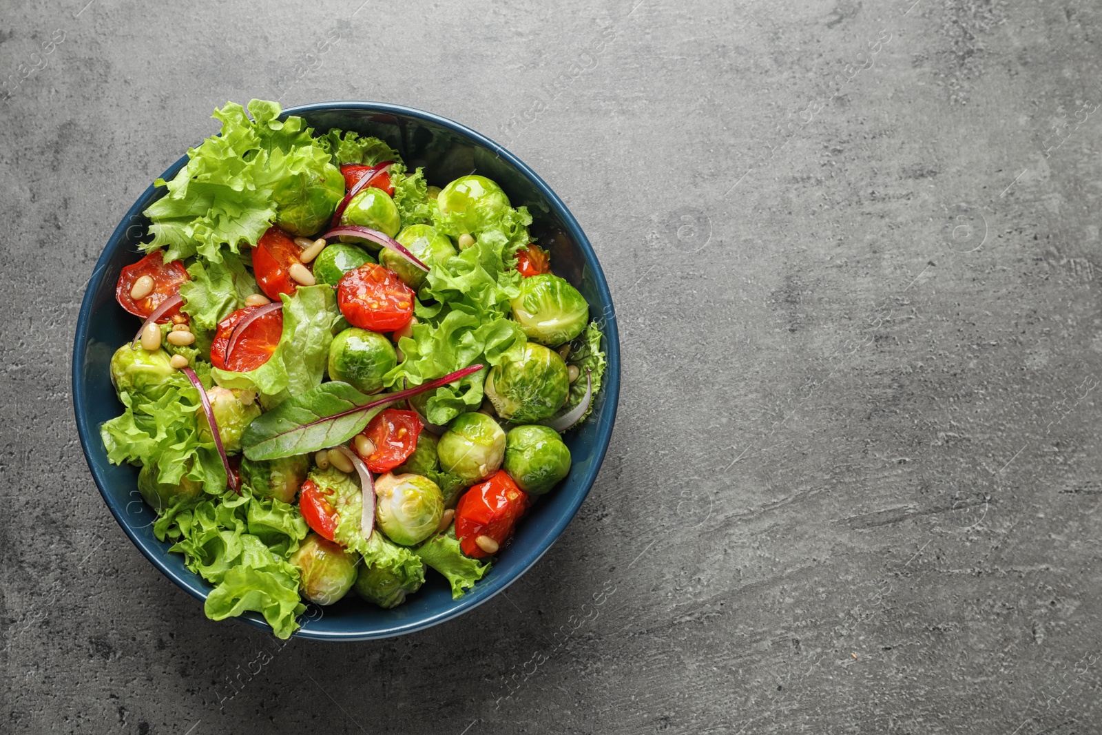 Photo of Bowl of salad with Brussels sprouts on grey background, top view. Space for text