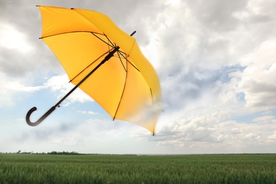 Image of Open umbrella blown by wind gust outdoors