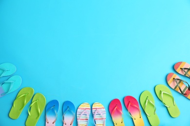 Photo of Different flip flops and space for text on blue background, flat lay. Summer beach accessories