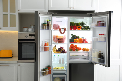 Photo of Open refrigerator filled with food in kitchen