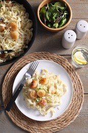 Photo of Delicious scallop pasta with onion served on wooden table, flat lay