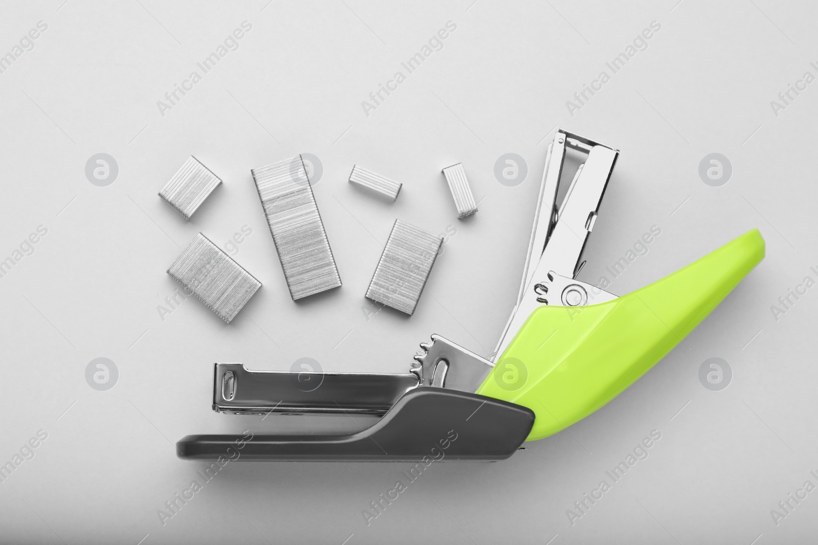 Photo of New bright stapler with staples on white background, fat lay. School stationery