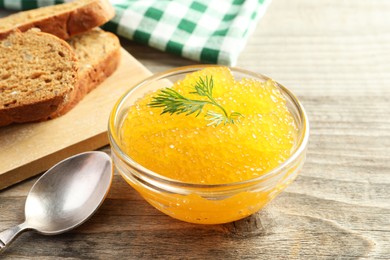 Photo of Fresh pike caviar in bowl and bread on wooden table, closeup