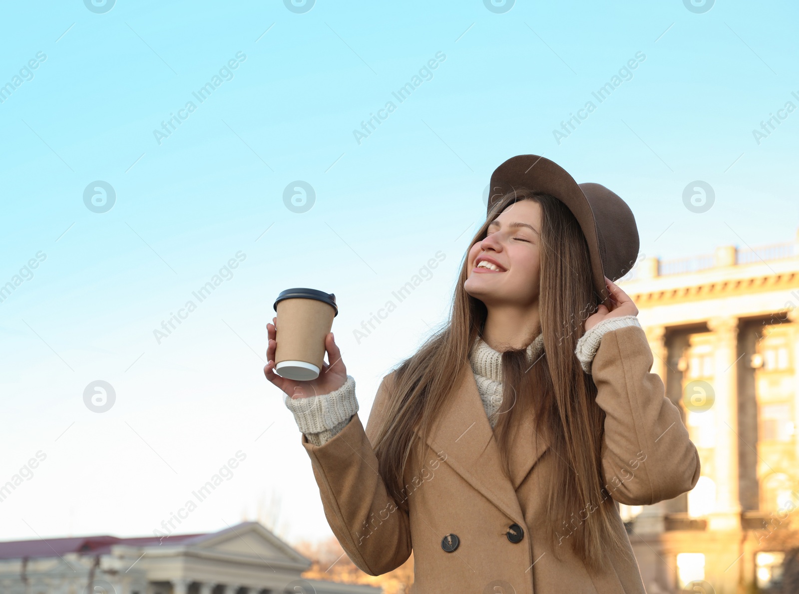 Photo of Young woman with cup of coffee on city street in morning