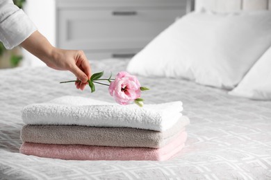 Photo of Woman putting beautiful flower on soft towels indoors, closeup