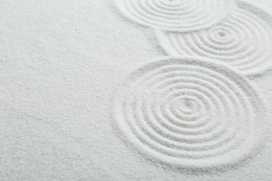 Photo of Zen rock garden. Circle patterns on white sand, closeup. Space for text