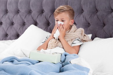 Photo of Ill boy suffering from cough in bed at home