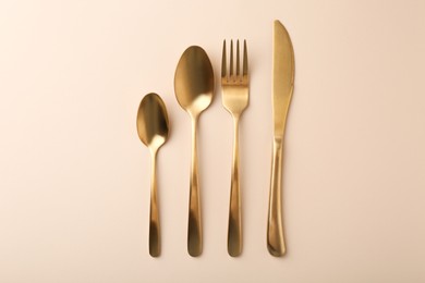 Photo of Stylish cutlery set on beige table, flat lay
