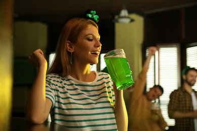 Photo of Young woman drinking green beer in pub. St. Patrick's Day celebration