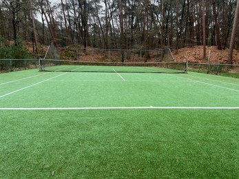Photo of Tennis court with artificial grass and net outdoors