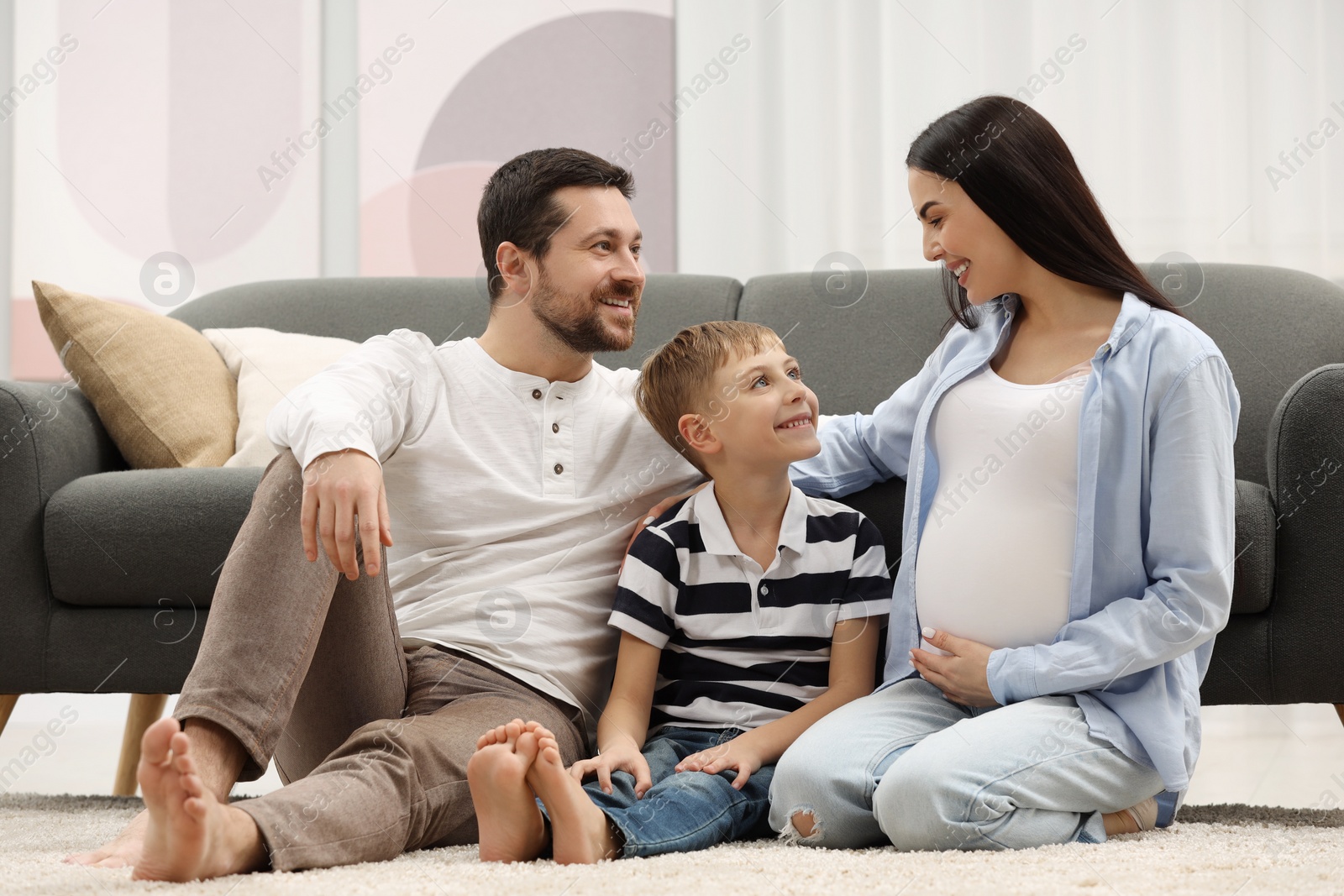 Photo of Pregnant woman spending time with her son and husband at home. Happy family