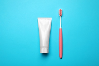 Photo of Blank tube of toothpaste and brush on color background, top view