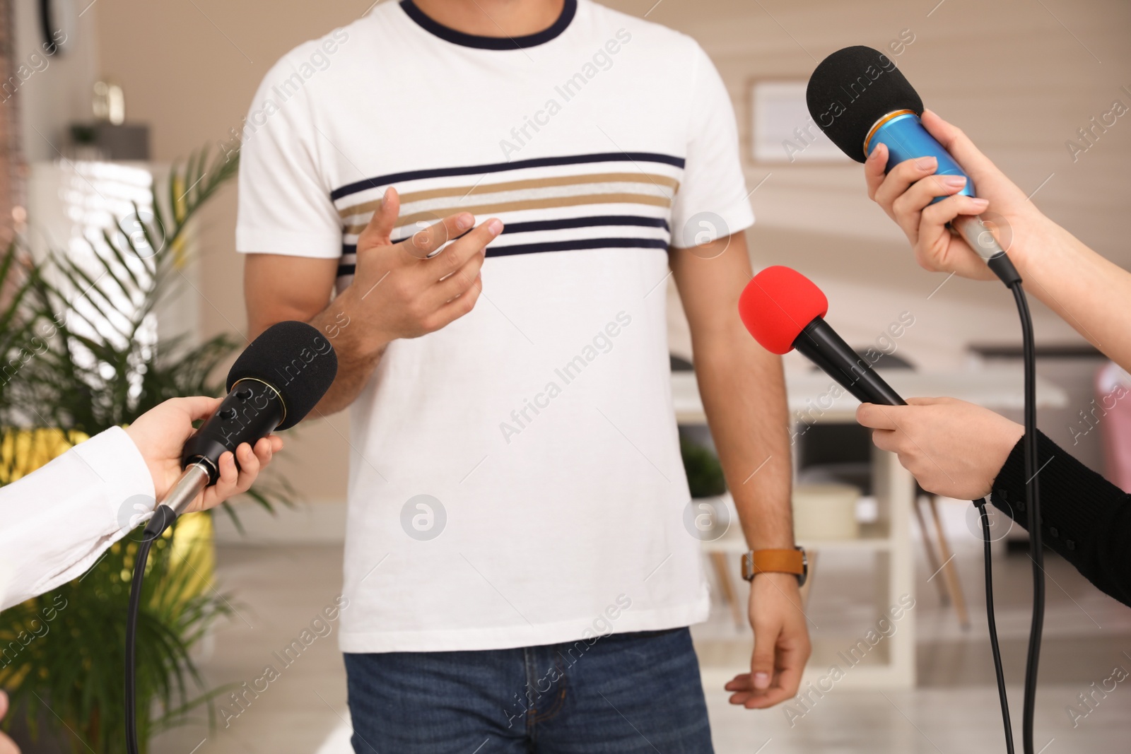 Photo of Group of journalists interviewing man in room, closeup